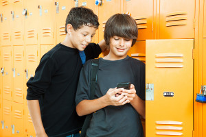 Two teenage boys playing a handheld video game in school by thei