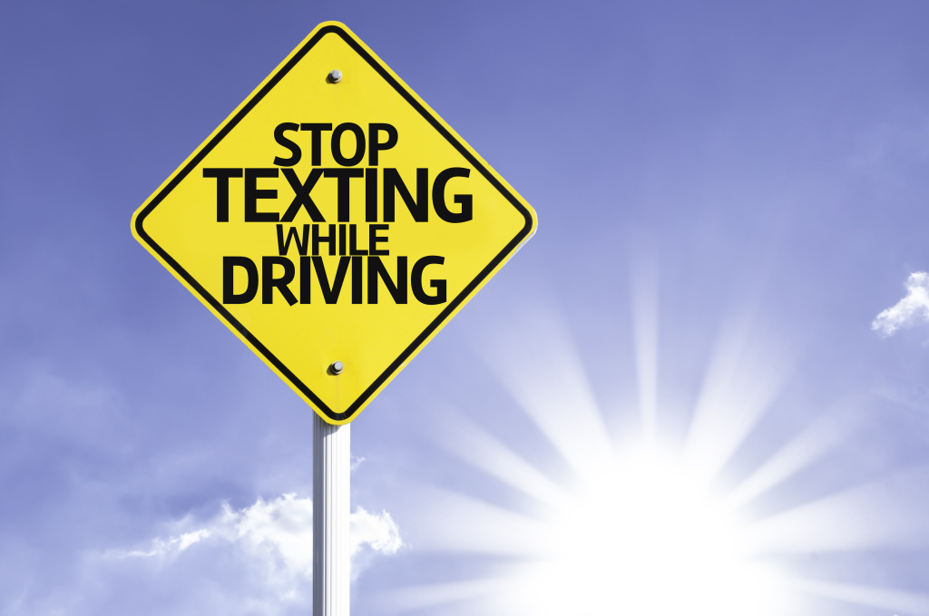 Stop Texting While Driving road sign with sun background